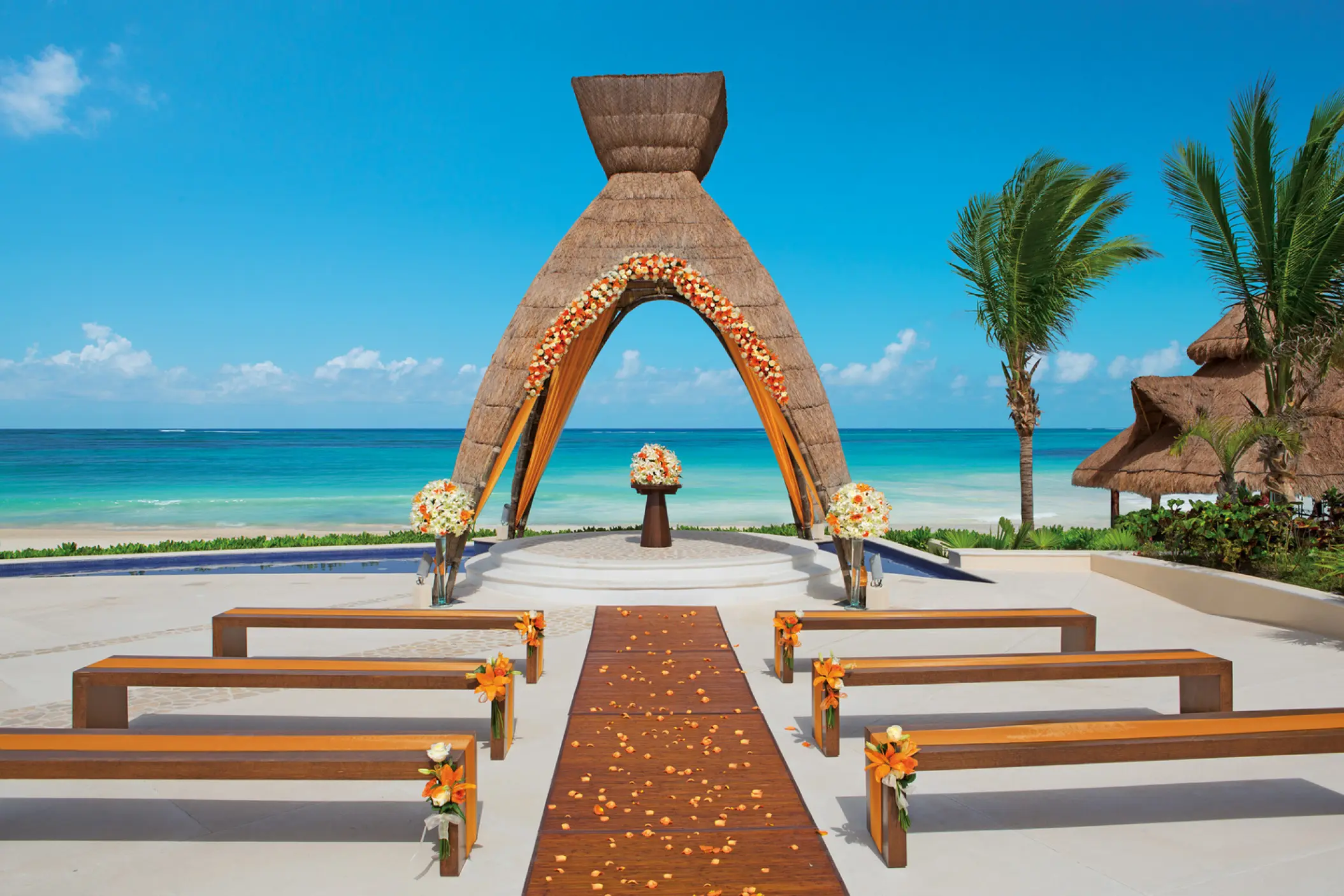 Thatch gazebo wedding ceremony with wooden benches at Dreams Riviera Cancun, Riviera Maya