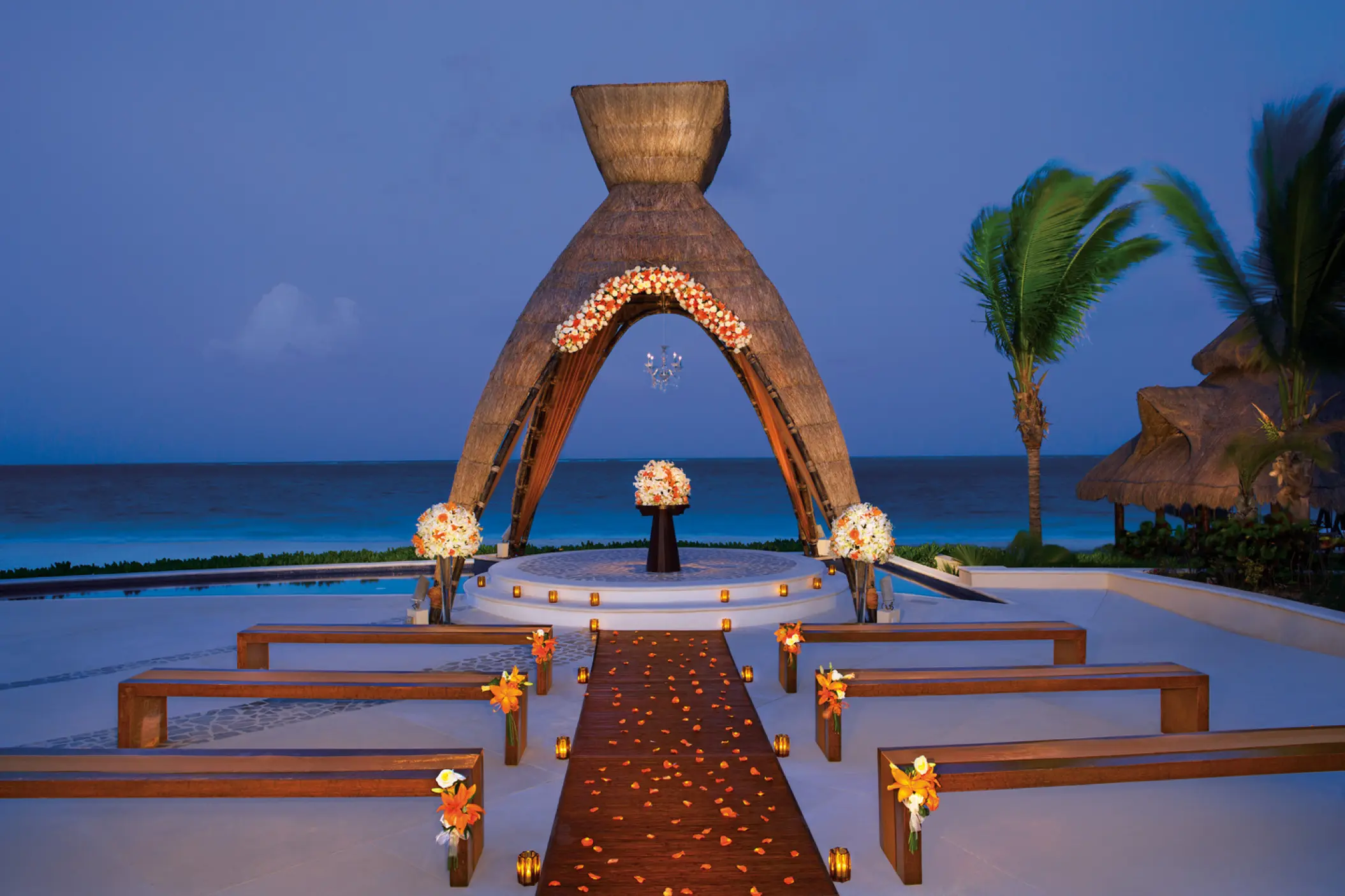 Thatched gazebo wedding ceremony with wooden benches at Dreams Riviera Cancun, Riviera Maya