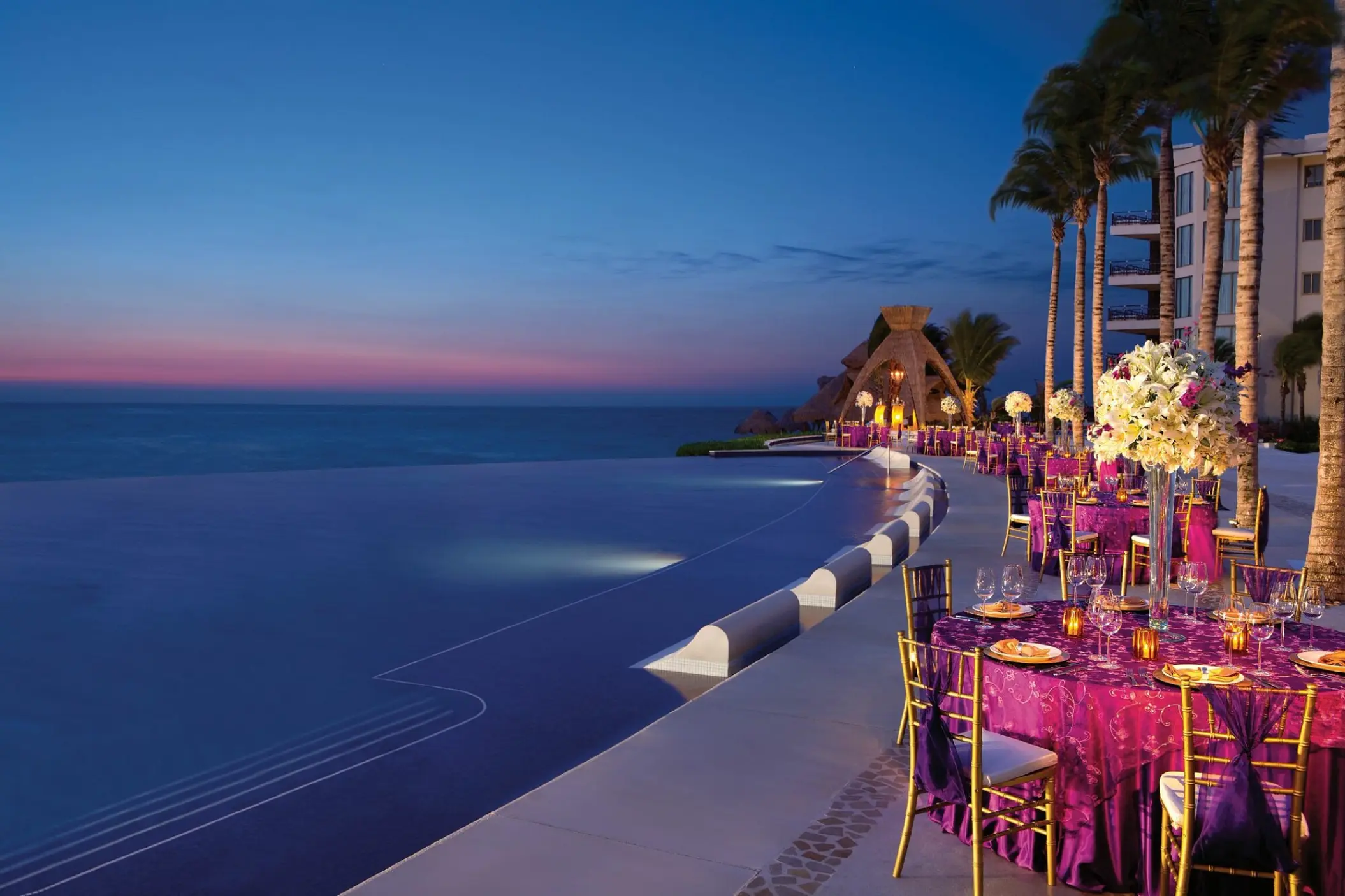 Evening wedding reception with purple linens by the infinity pool at Dreams Riviera Cancun, Riviera Maya