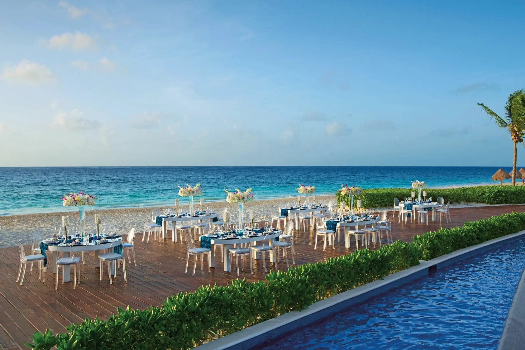 Oceanfront wedding reception tables on a wooden terrace at Dreams Riviera Cancun, Riviera Maya