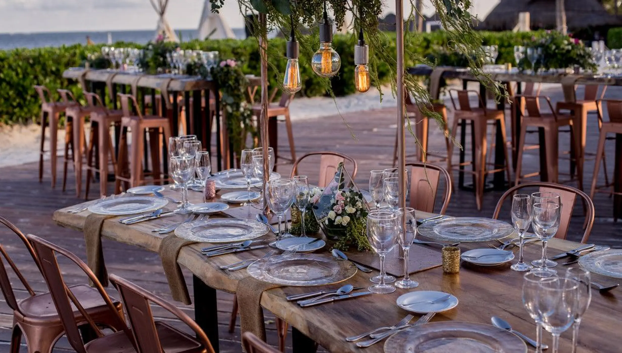 Outdoor wedding reception setup with copper chairs and Edison bulbs at Dreams Riviera Cancun, Riviera Maya