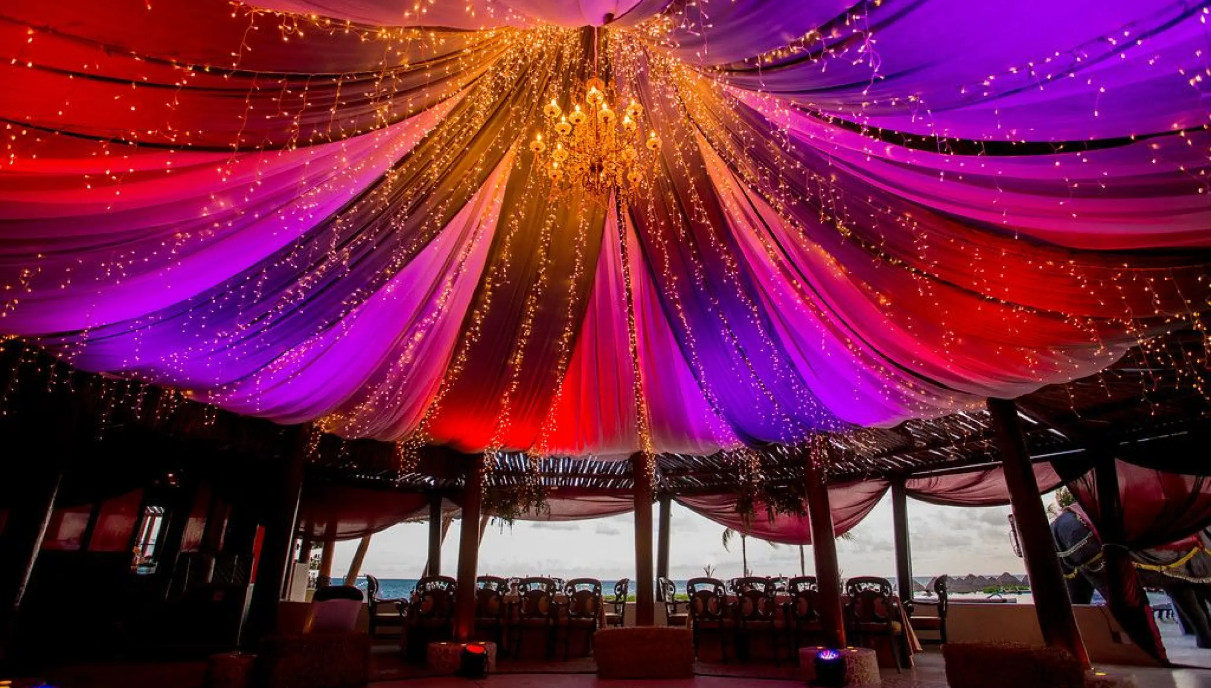 Indoor wedding reception with colorful lit drapery and fairy lights at Dreams Riviera Cancun, Riviera Maya
