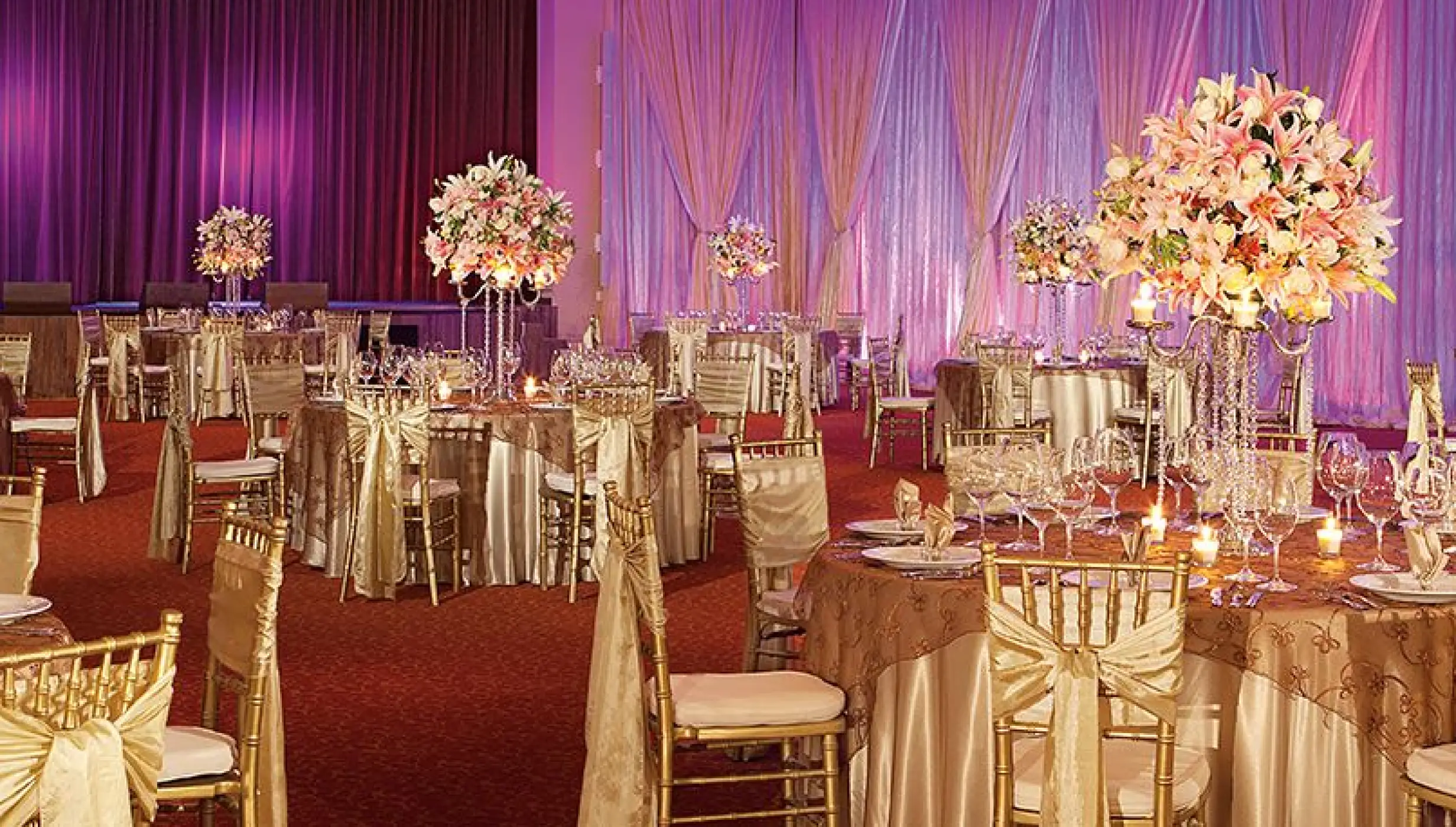 Indoor ballroom wedding reception with gold linens and tall floral centerpieces at Dreams Riviera Cancun, Riviera Maya