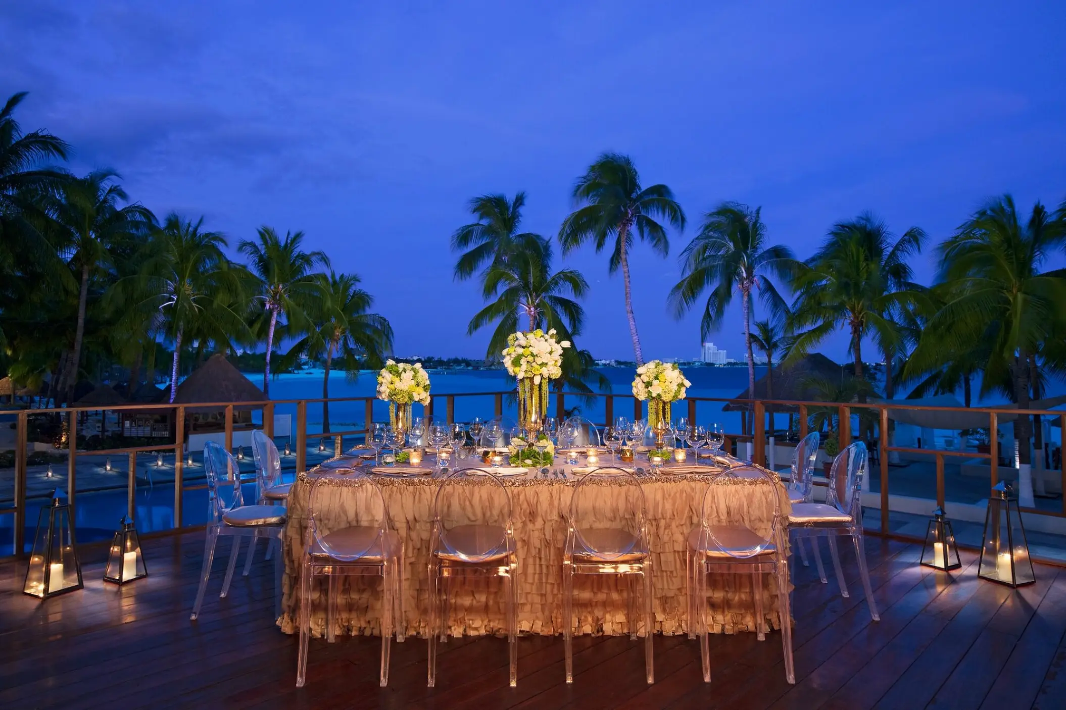 Outdoor wedding reception table with white flowers and ghost chairs at Dreams Sands Cancun, Cancun