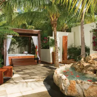 Spa terrace with a hot tub, gazebo, and stone water feature at Dreams Sands Cancun