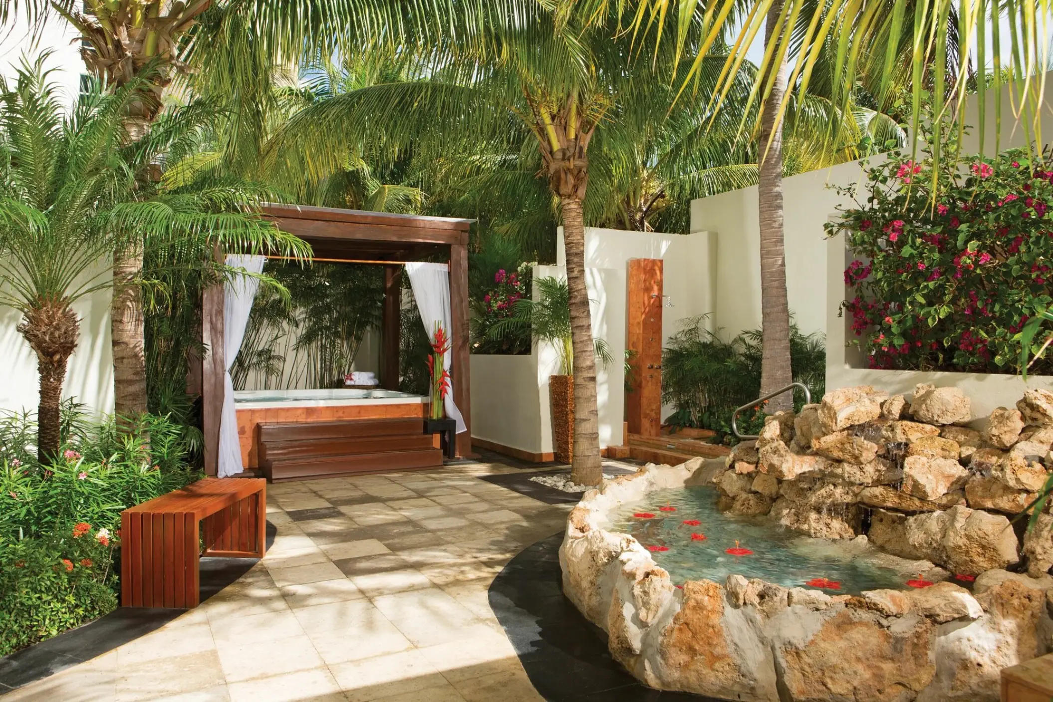 Spa terrace with a hot tub, gazebo, and stone water feature at Dreams Sands Cancun