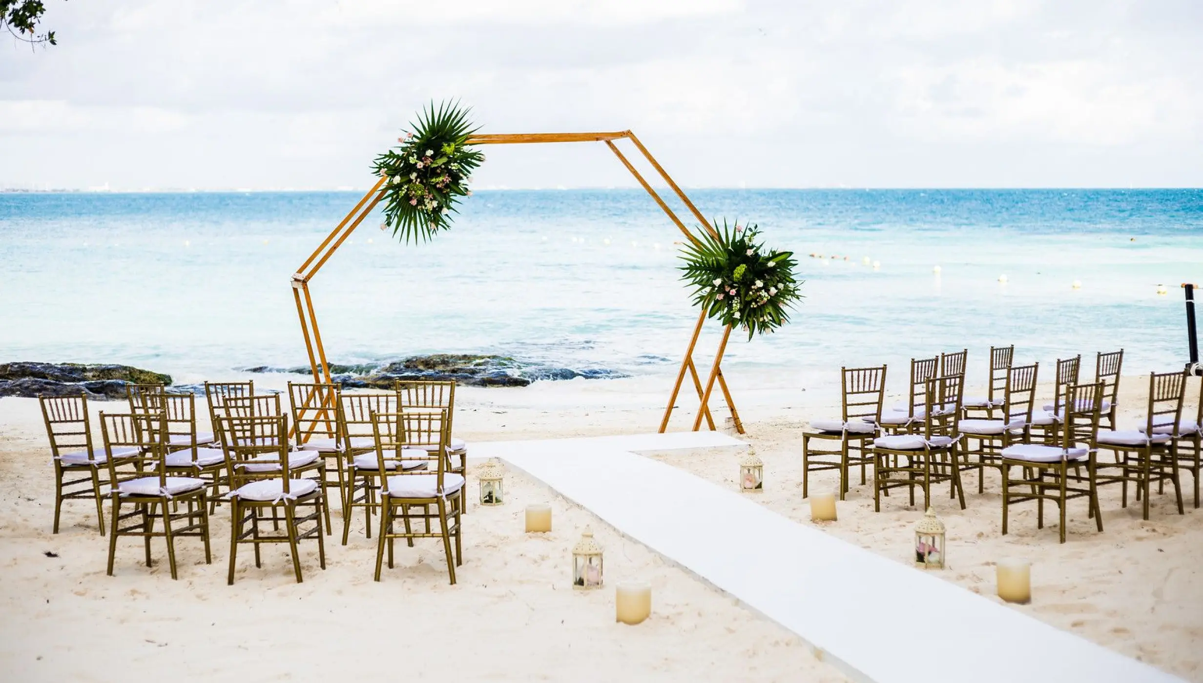 Beachfront wedding ceremony setup with a wooden hexagon arch at Dreams Sands Cancun