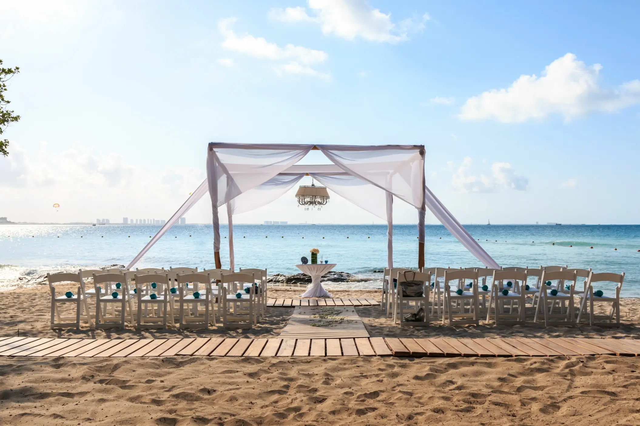 Beachfront wedding ceremony setup with white huppah and chairs at Dreams Sands Cancun
