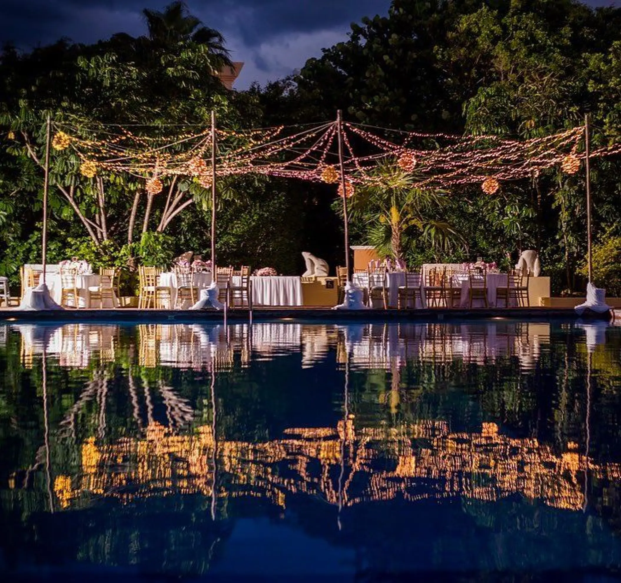 Poolside wedding reception with string lights at Dreams Sapphire, Riviera Maya