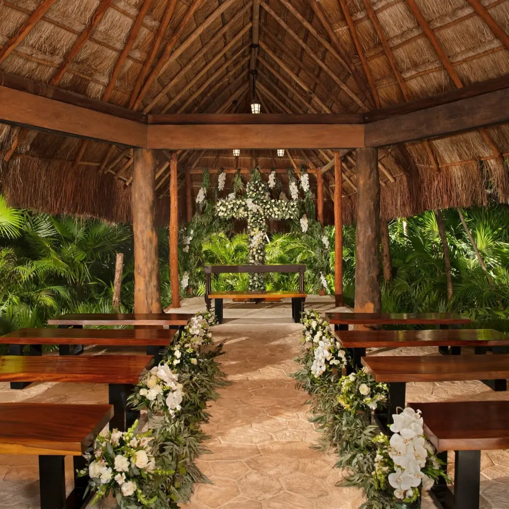 Thatched roof chapel with wooden benches for a wedding ceremony at Dreams Sapphire, Riviera Maya