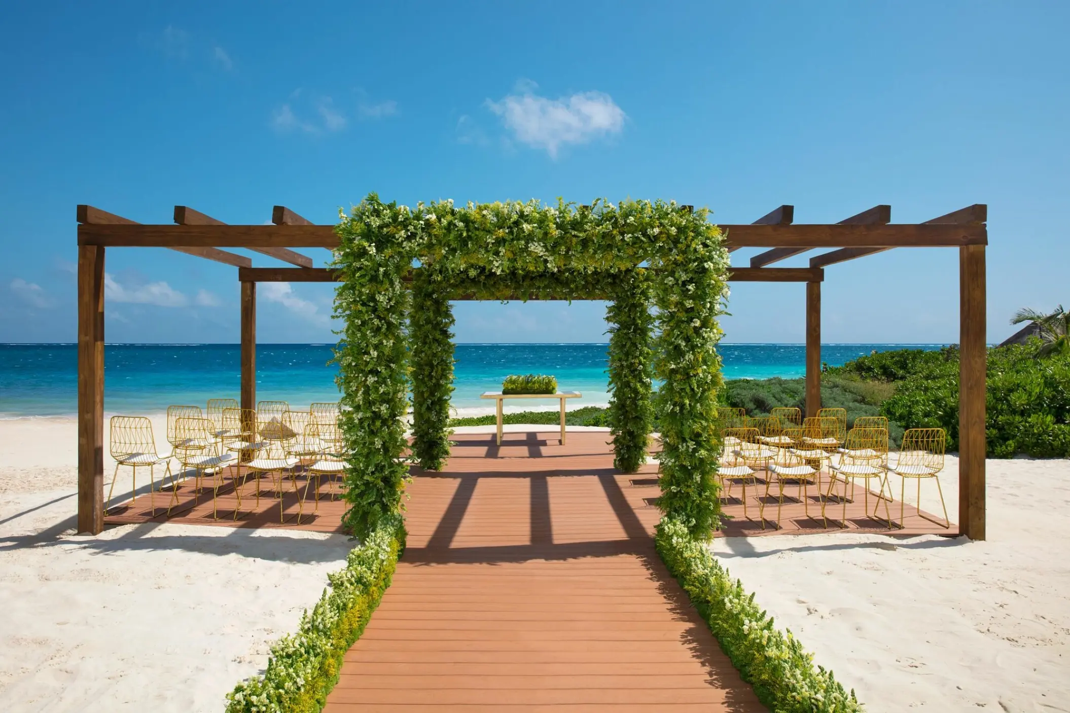 Beachfront wedding ceremony gazebo with greenery and gold chairs at Dreams Sapphire, Riviera Maya