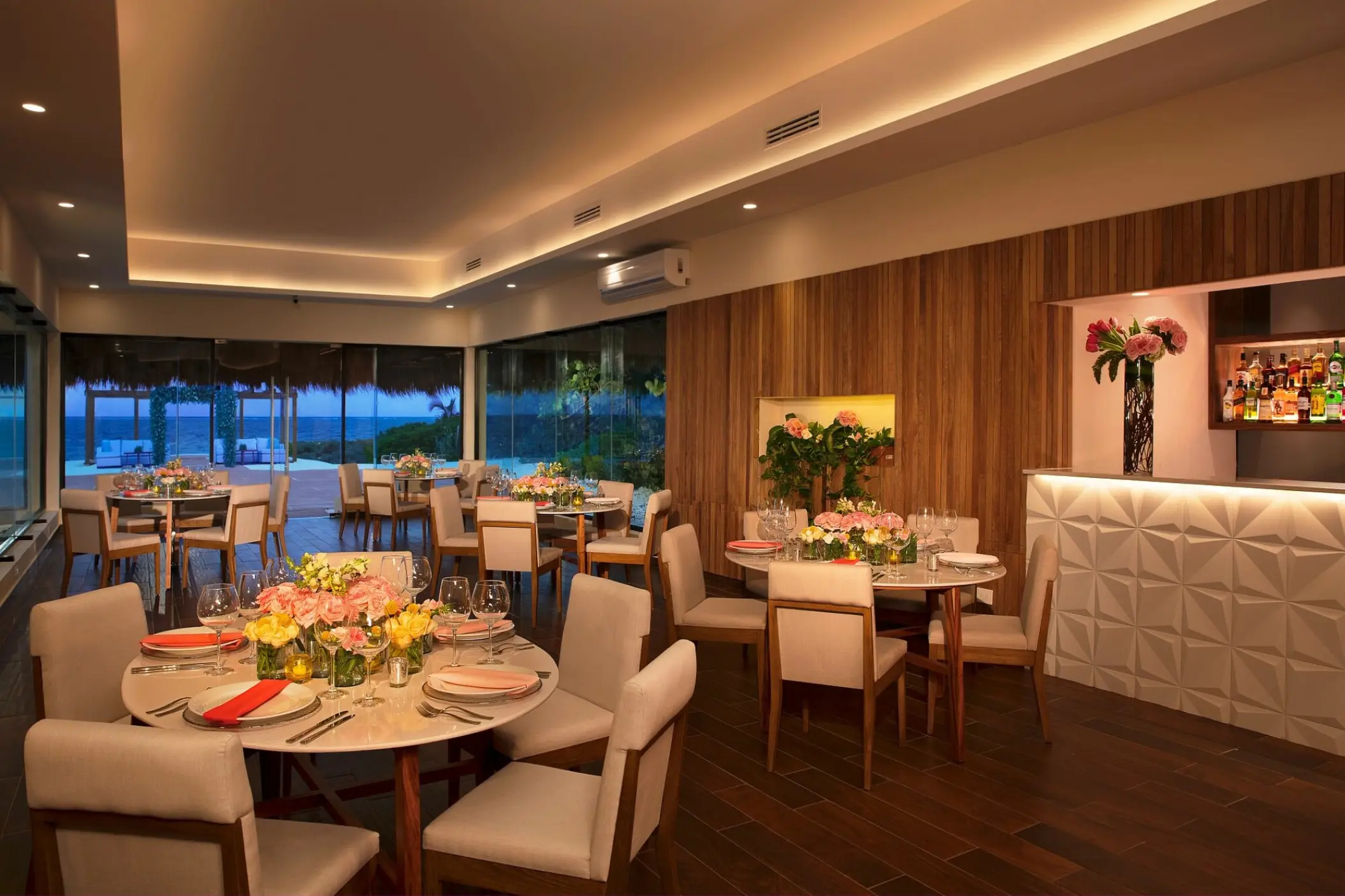 Indoor wedding reception with floral centerpieces and bar at Dreams Sapphire, Riviera Maya
