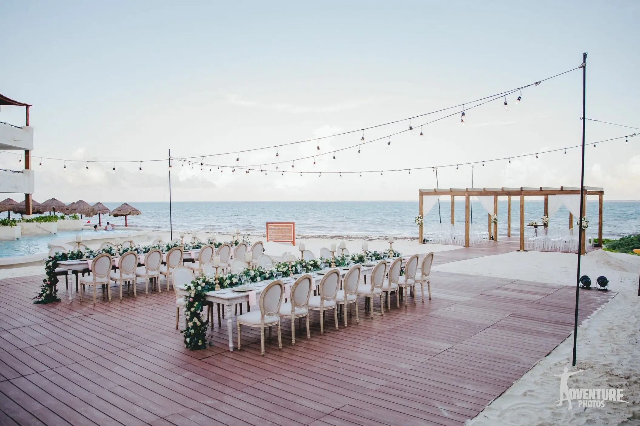 Beachfront wedding reception setup on a terrace with string lights at Dreams Sapphire, Riviera Maya