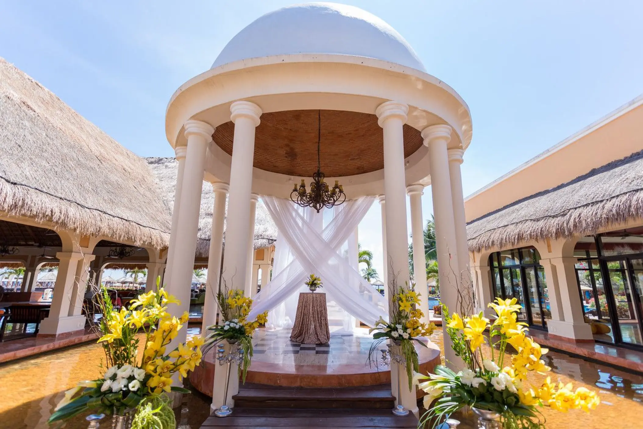White domed wedding gazebo with yellow floral arrangements at Dreams Sapphire, Riviera Maya