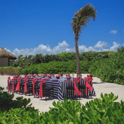 Beachfront wedding reception table with striped linens and red sashes at Dreams Tulum, Tulum