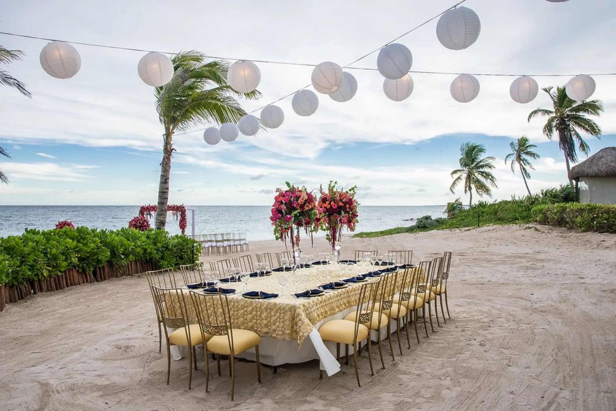 Beachfront wedding reception table with gold decor and white lanterns at Dreams Tulum, Tulum