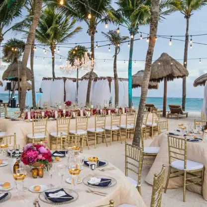 Beachfront wedding reception setup with gold chairs and string lights at Dreams Tulum, Tulum
