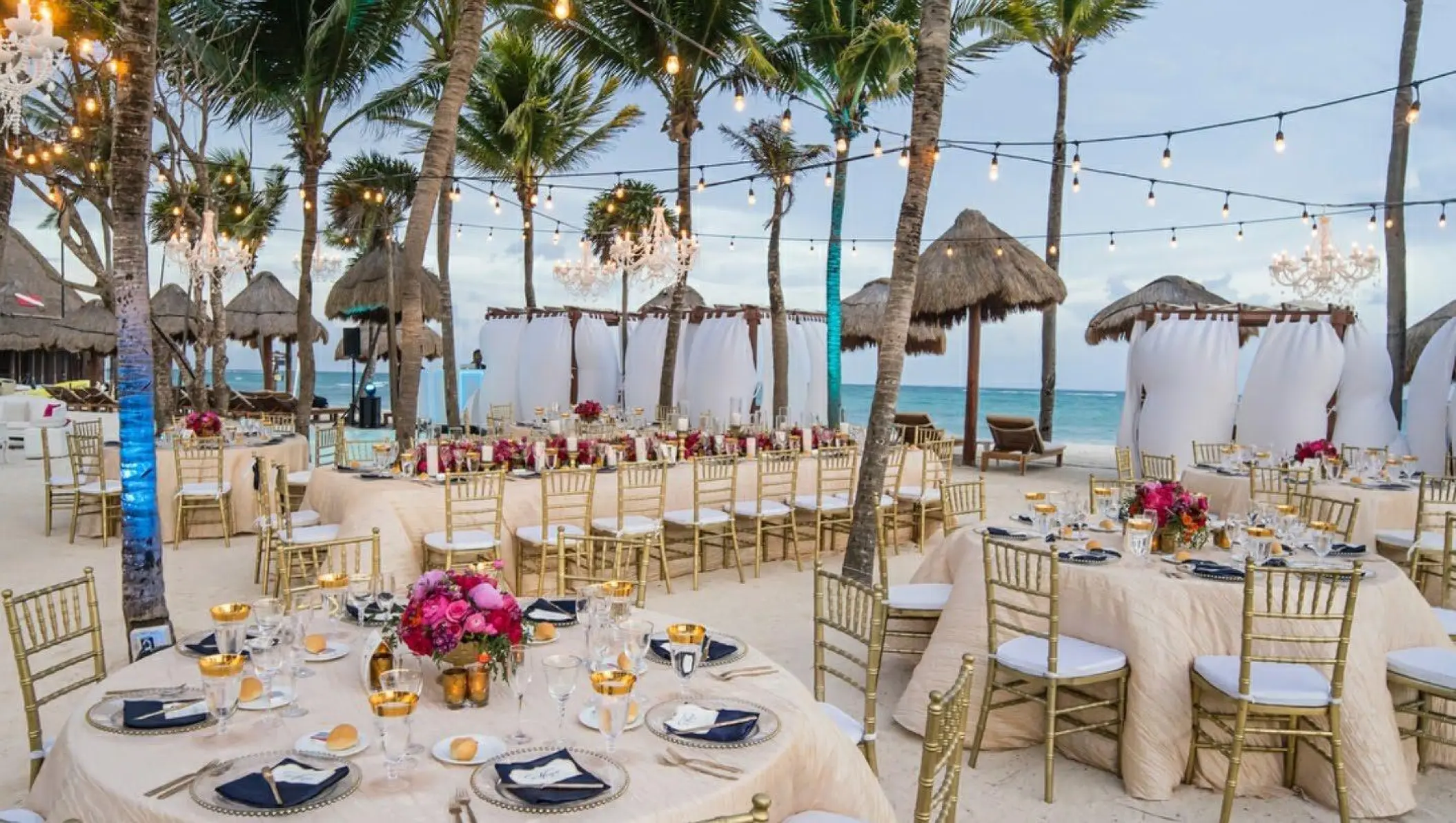 Beachfront wedding reception setup with gold chairs and string lights at Dreams Tulum, Tulum