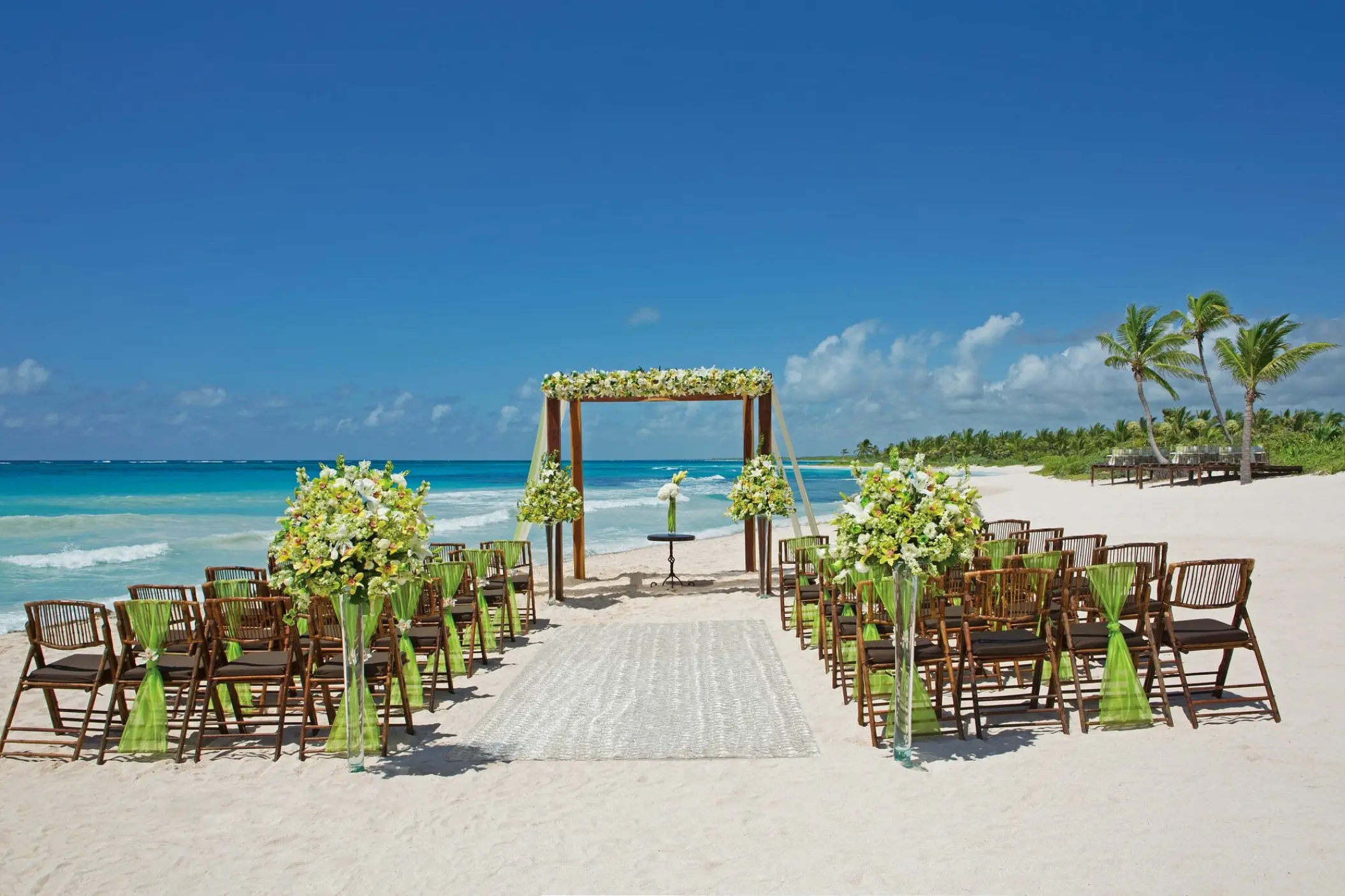 Beachfront wedding ceremony with a floral wooden arch at Dreams Tulum, Tulum