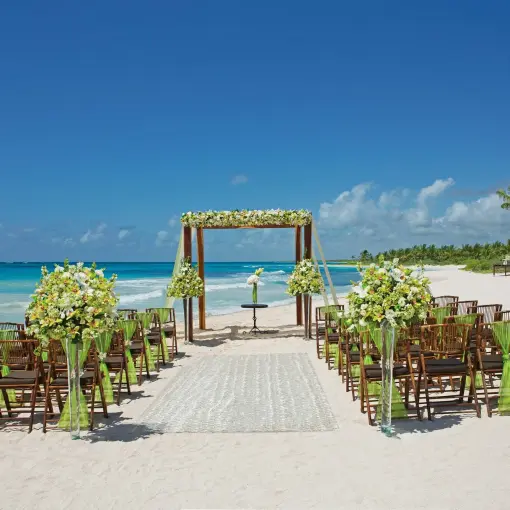 Beachfront wedding ceremony with a floral wooden arch at Dreams Tulum, Tulum