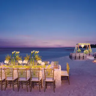 Beachfront wedding reception and ceremony setup at dusk at Dreams Tulum