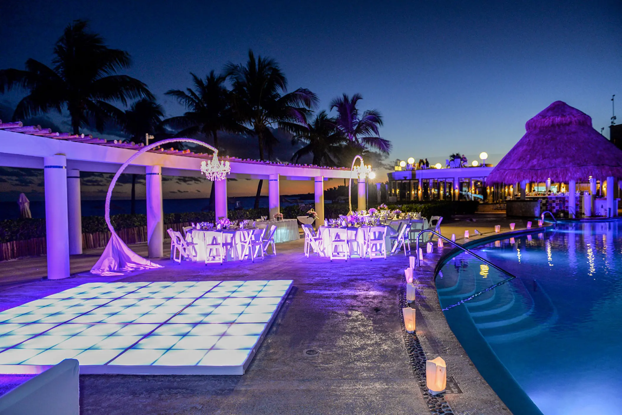Evening wedding reception with a lighted dance floor and pool venue at Dreams Tulum, Tulum