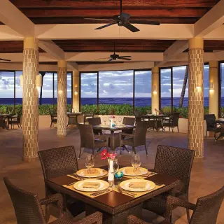 Open-air seaside restaurant with wicker chairs and ocean views at Dreams Tulum, Tulum