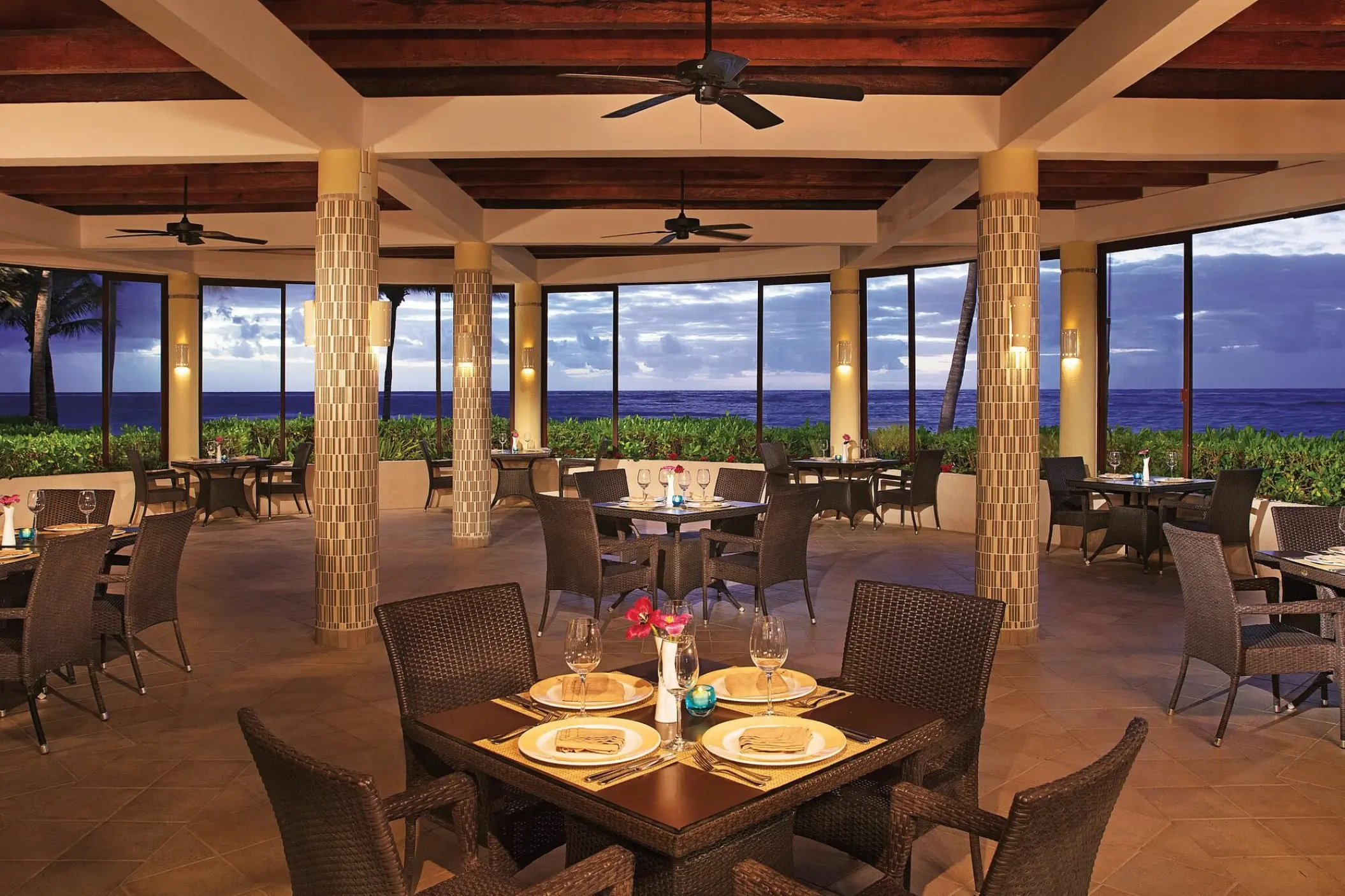 Open-air seaside restaurant with wicker chairs and ocean views at Dreams Tulum, Tulum
