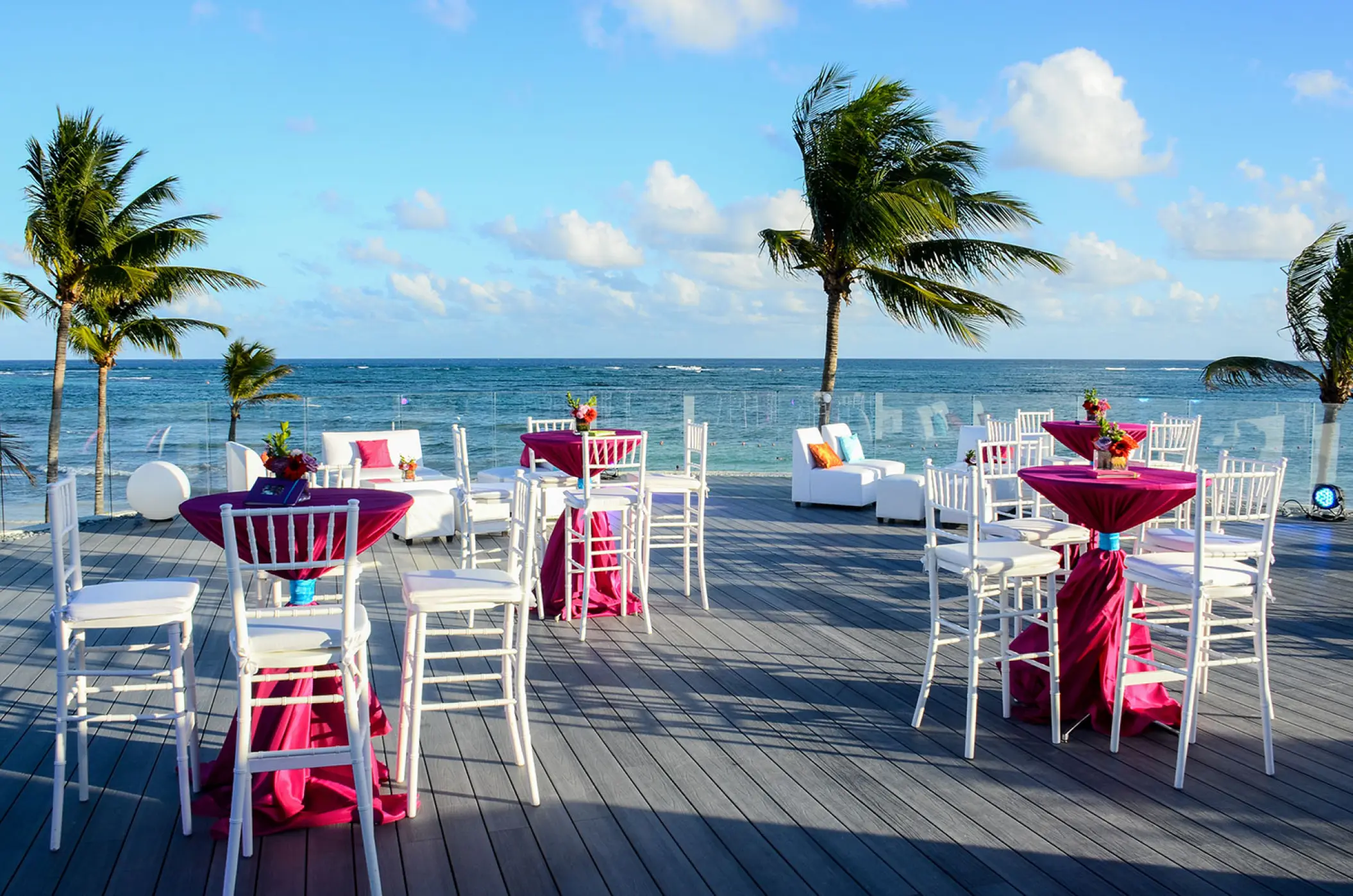 Oceanfront wedding reception setup with magenta linens on the terrace at Dreams Tulum, Tulum