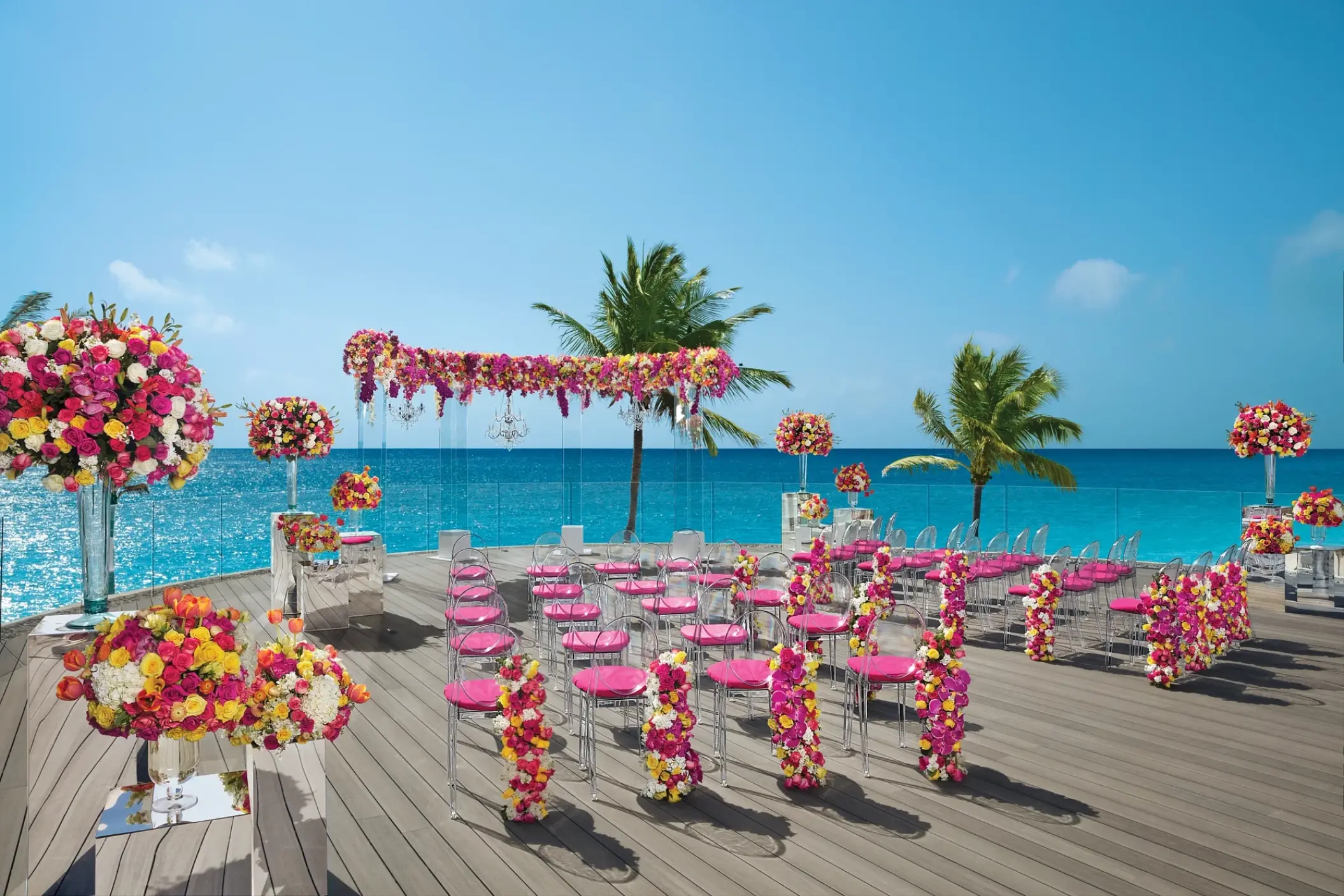 Rooftop wedding ceremony set with pink flowers and clear chairs at Dreams Tulum, Tulum