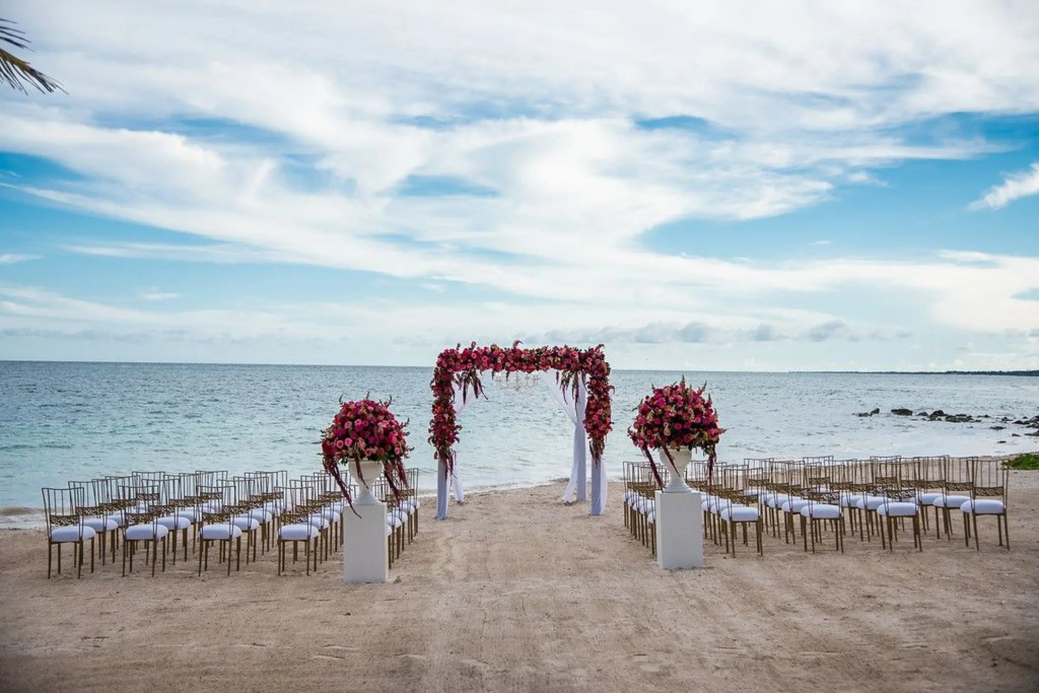 Beachfront wedding ceremony setup with red floral arch at Dreams Tulum, Tulum