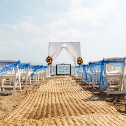 Beachfront wedding ceremony with white chairs and blue sashes at Dreams Vallarta Bay, Puerto Vallarta
