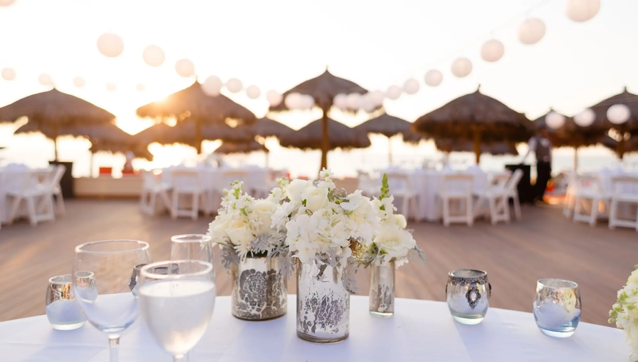 Outdoor wedding reception with white floral centerpieces and string lights at Dreams Vallarta Bay, Puerto Vallarta