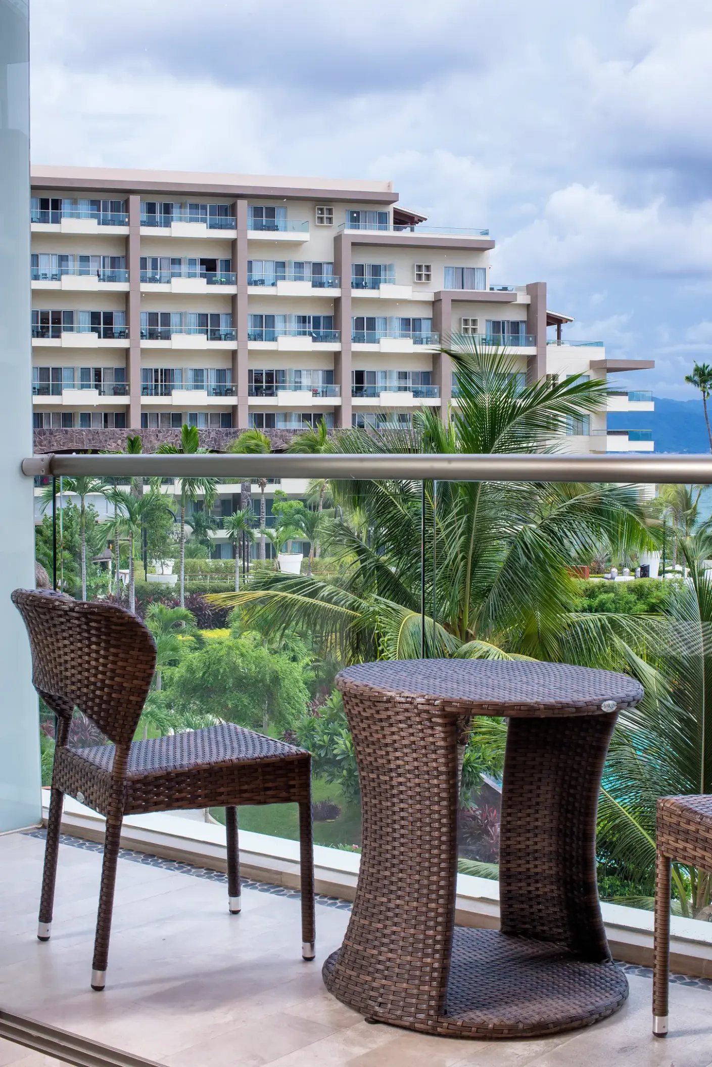 Private balcony with wicker furniture overlooking the grounds at Dreams Vallarta Bay, Puerto Vallarta