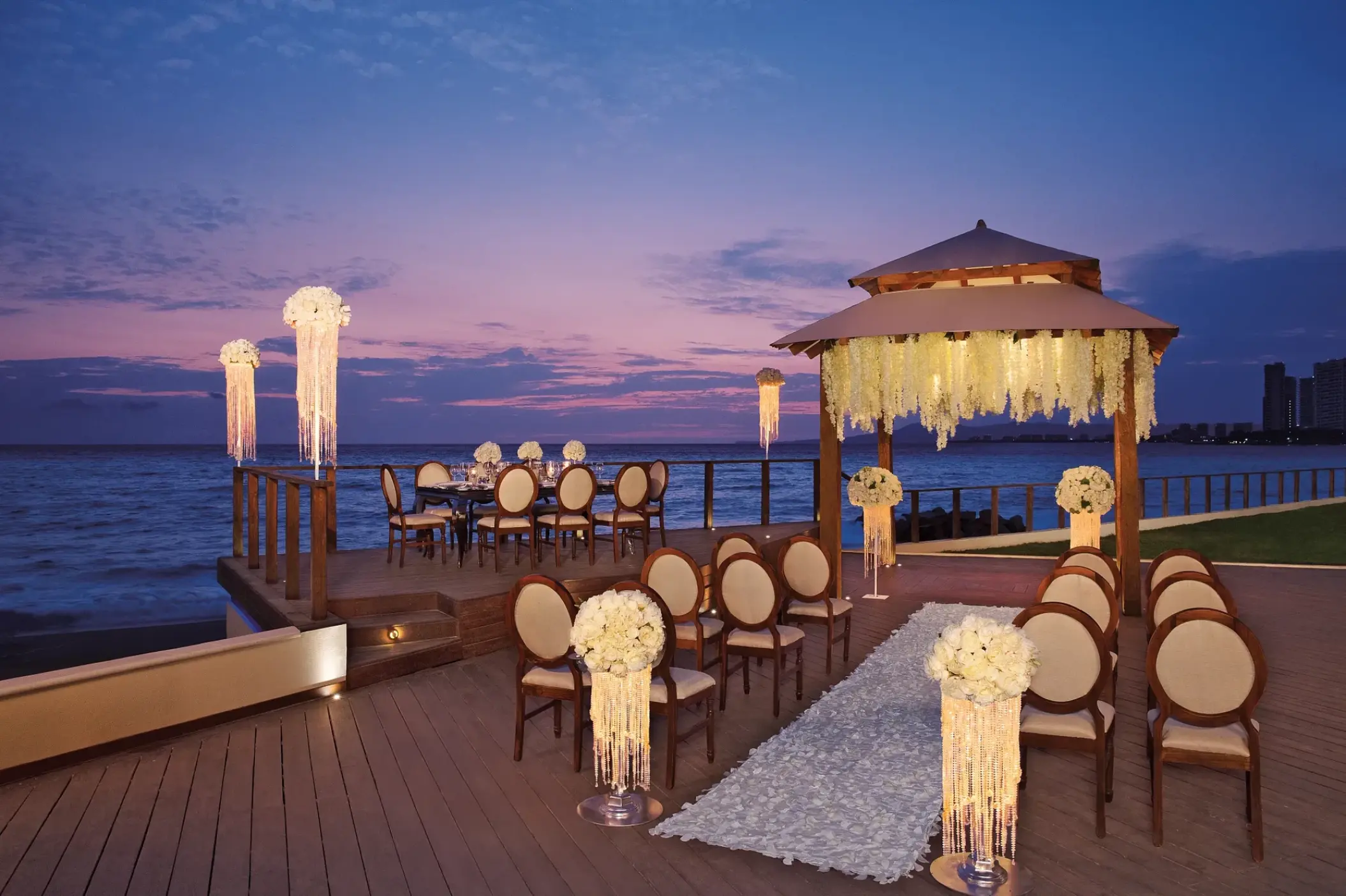 Waterfront wedding ceremony and reception setup at dusk at Dreams Vallarta Bay, Puerto Vallarta