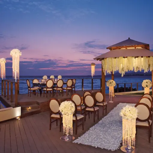 Waterfront wedding ceremony and reception setup at dusk at Dreams Vallarta Bay, Puerto Vallarta