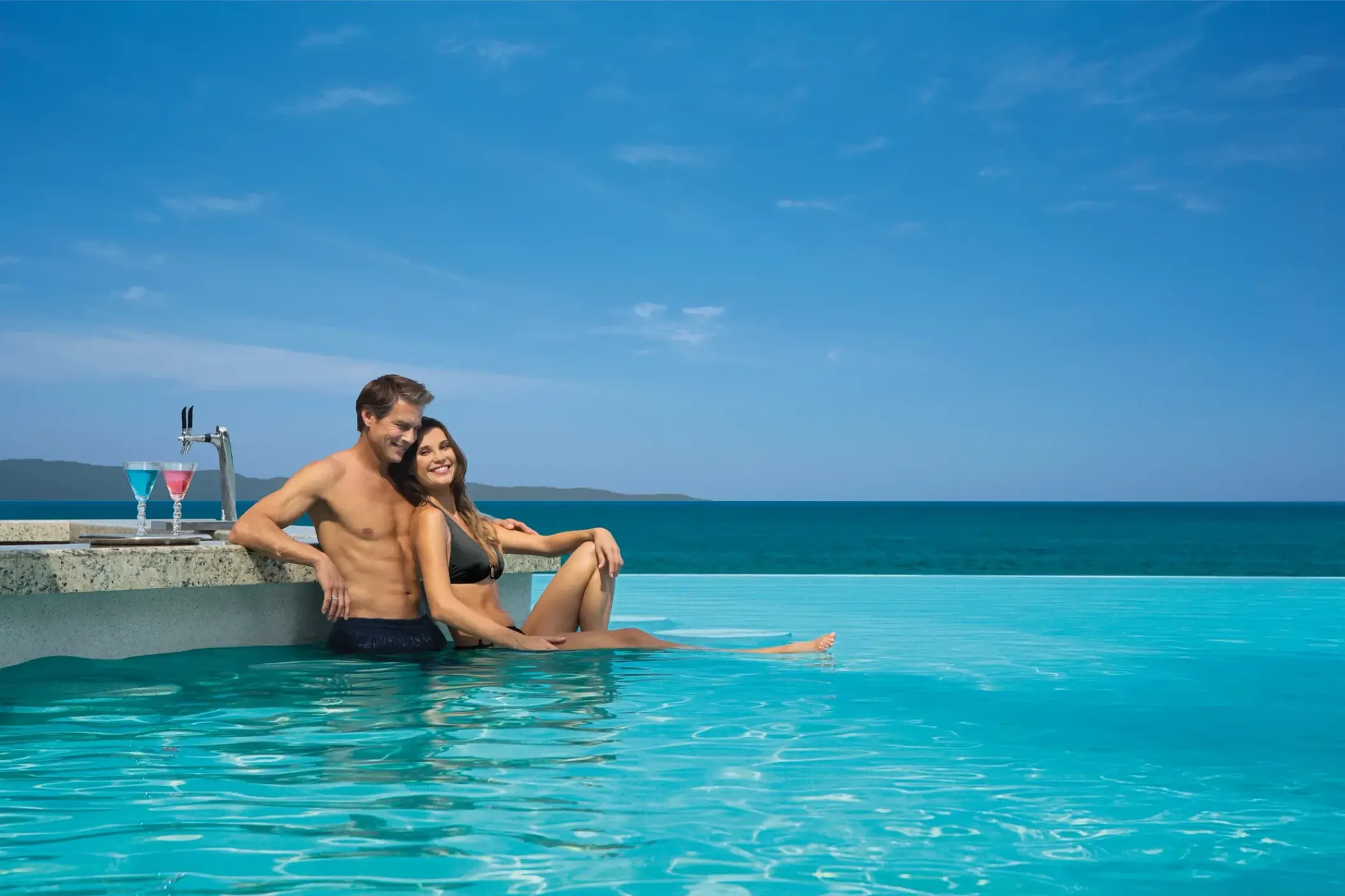Couple relaxing at a swim-up bar in the infinity pool at Dreams Vallarta Bay, Puerto Vallarta