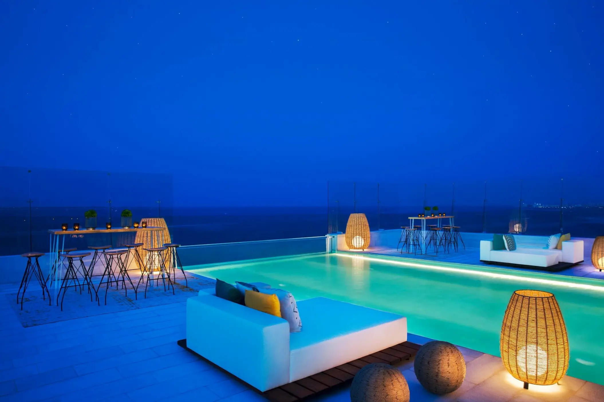 Rooftop terrace and pool with bar seating at night at Dreams Vista Cancun