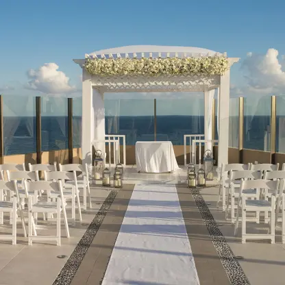 Rooftop wedding ceremony setup with white chairs and floral gazebo at El Dorado Seaside Suites, Riviera Maya