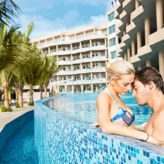 A couple relaxing in a blue tiled pool at El Dorado Seaside Suites, Riviera Maya