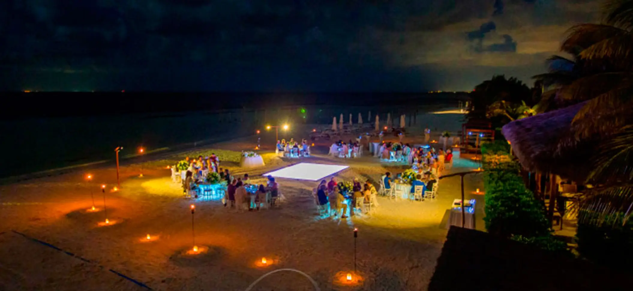 Nighttime beach wedding reception with glowing dance floor at El Dorado Maroma, Riviera Maya