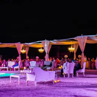 Beachfront wedding reception at night with lit dance floor and chandeliers at El Dorado Maroma, Riviera Maya