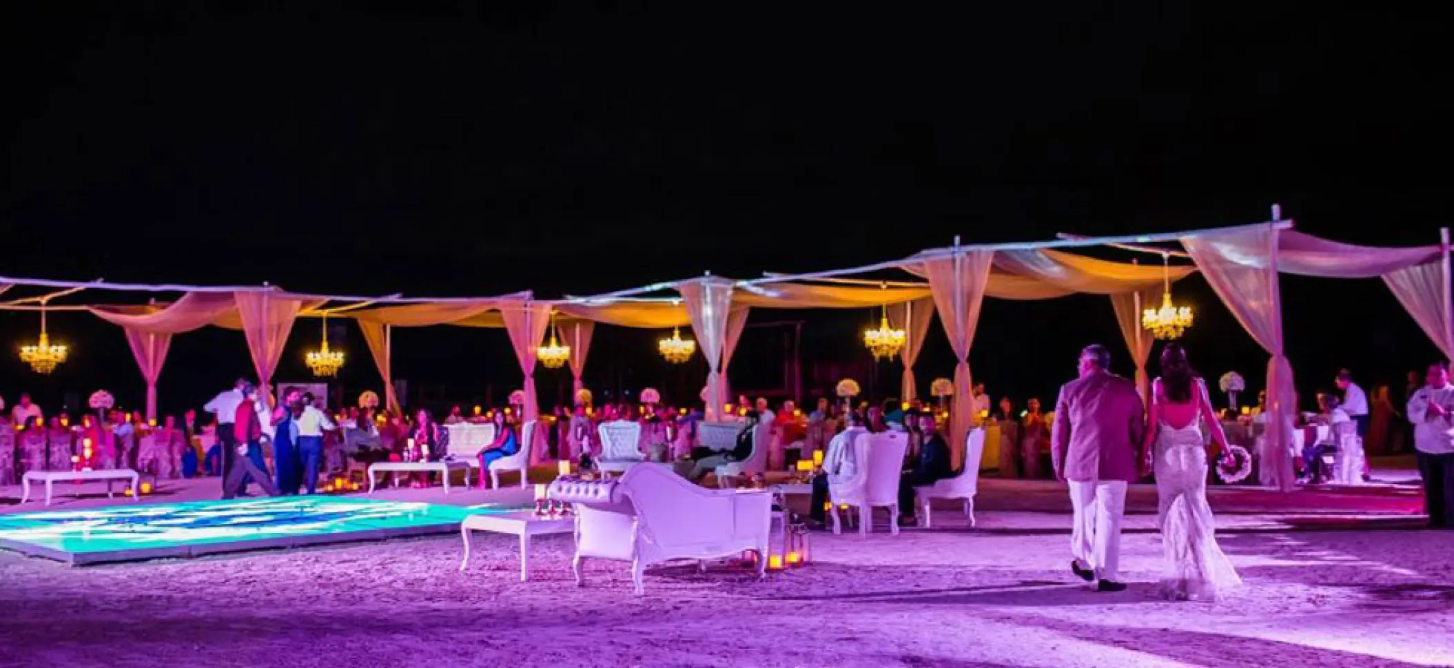 Beachfront wedding reception at night with lit dance floor and chandeliers at El Dorado Maroma, Riviera Maya