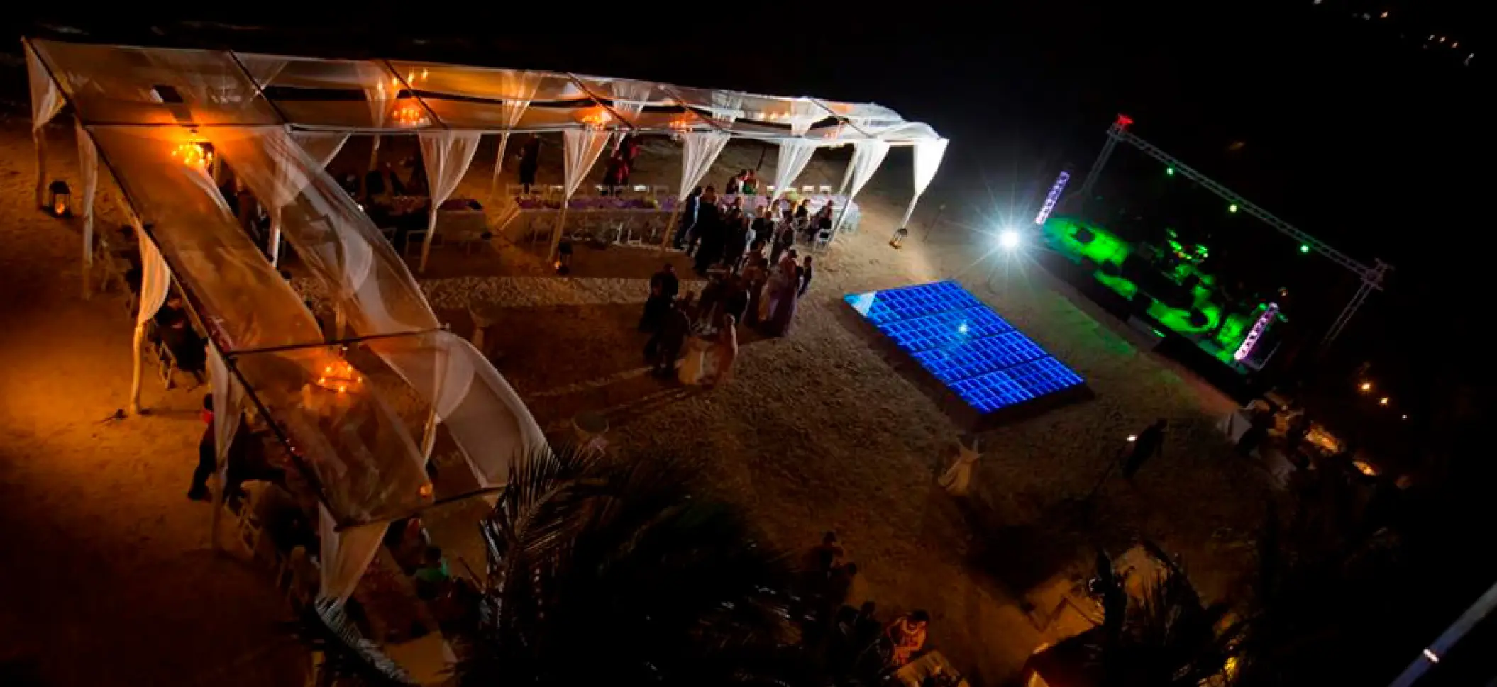 Overhead view of a beach wedding reception with an illuminated dance floor at El Dorado Maroma, Riviera Maya
