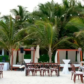 Beachfront wedding reception with wooden tables and string lights at El Dorado Maroma, Riviera Maya