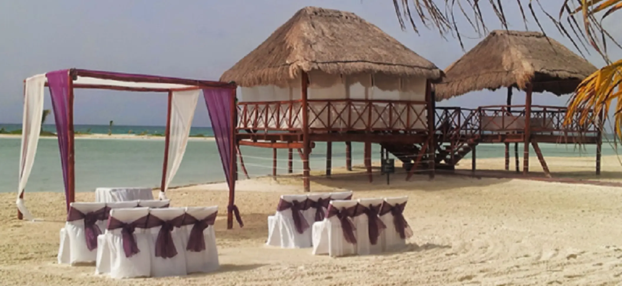 Beachfront wedding ceremony with purple huppah and chairs at El Dorado Maroma, Riviera Maya