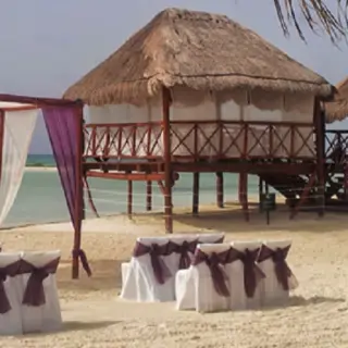 Beachfront wedding ceremony with purple huppah and chairs at El Dorado Maroma, Riviera Maya