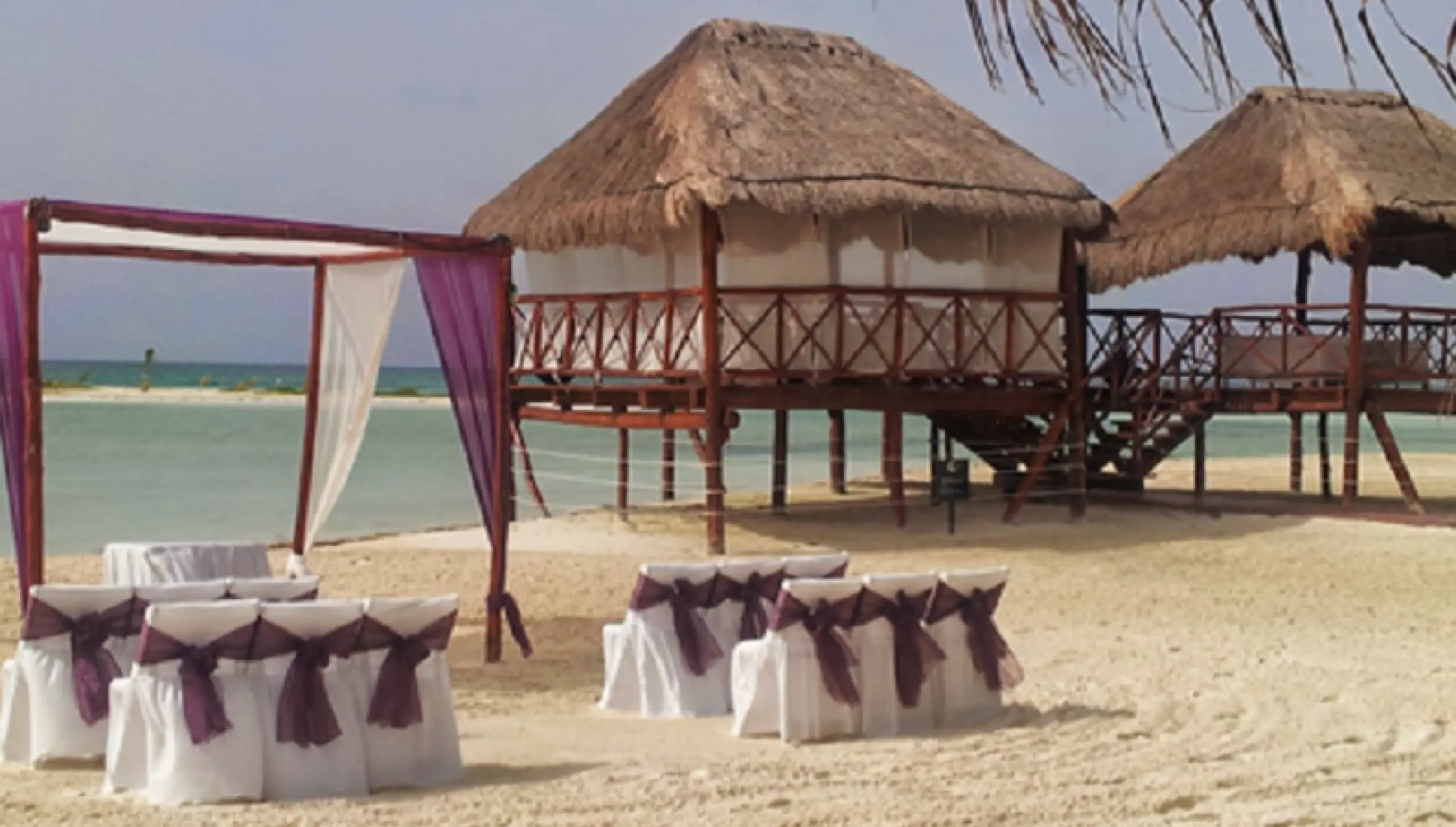 Beachfront wedding ceremony with purple huppah and chairs at El Dorado Maroma, Riviera Maya