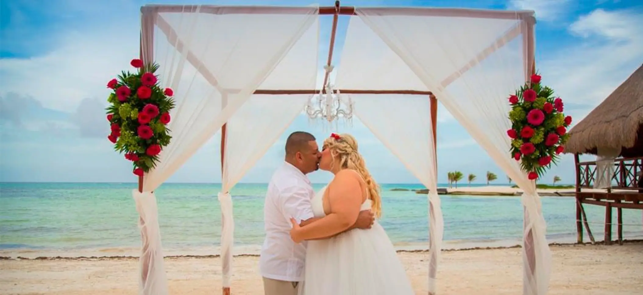 Couple kissing under a beach ceremony huppah at El Dorado Maroma, Riviera Maya