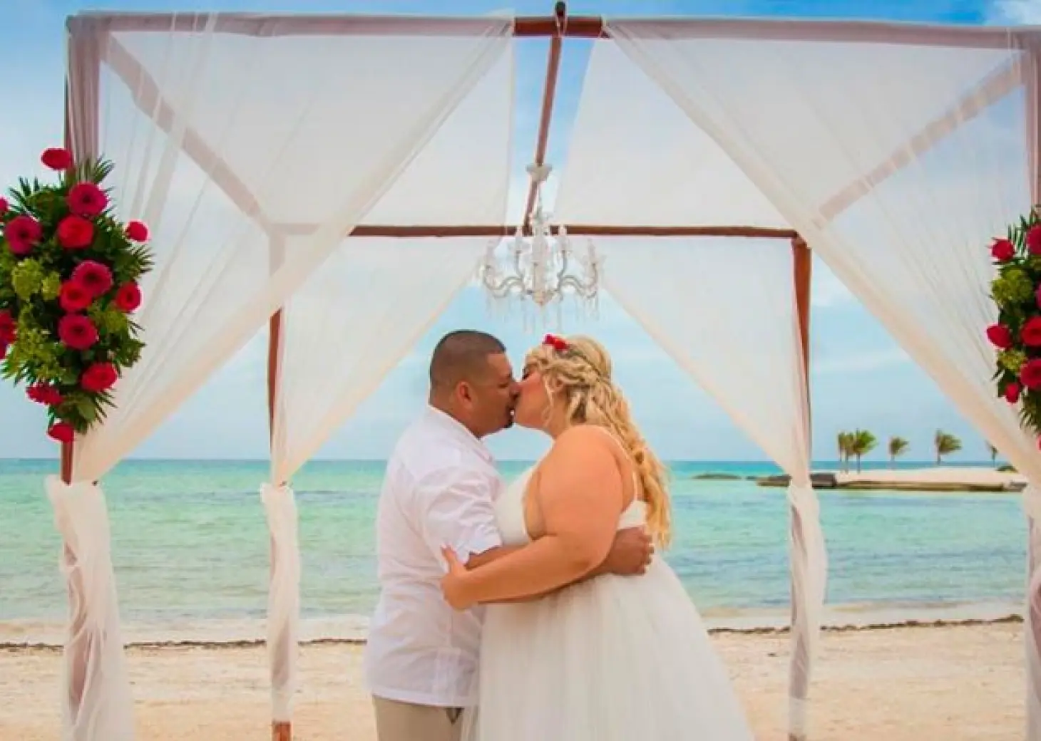 Couple kissing under a beach ceremony huppah at El Dorado Maroma, Riviera Maya